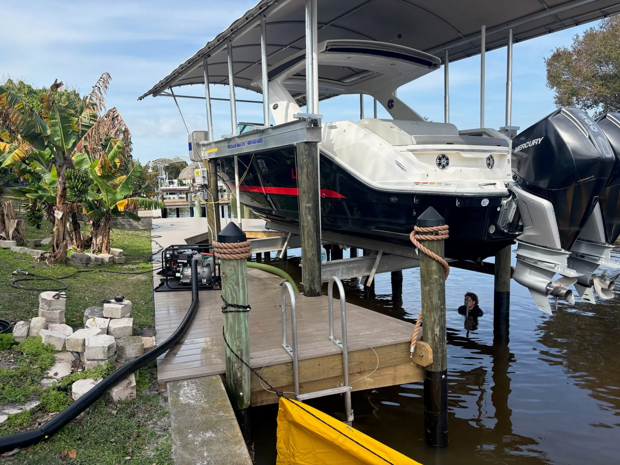 Dock & Dredge: hose beside a boat lift with a worker in the water