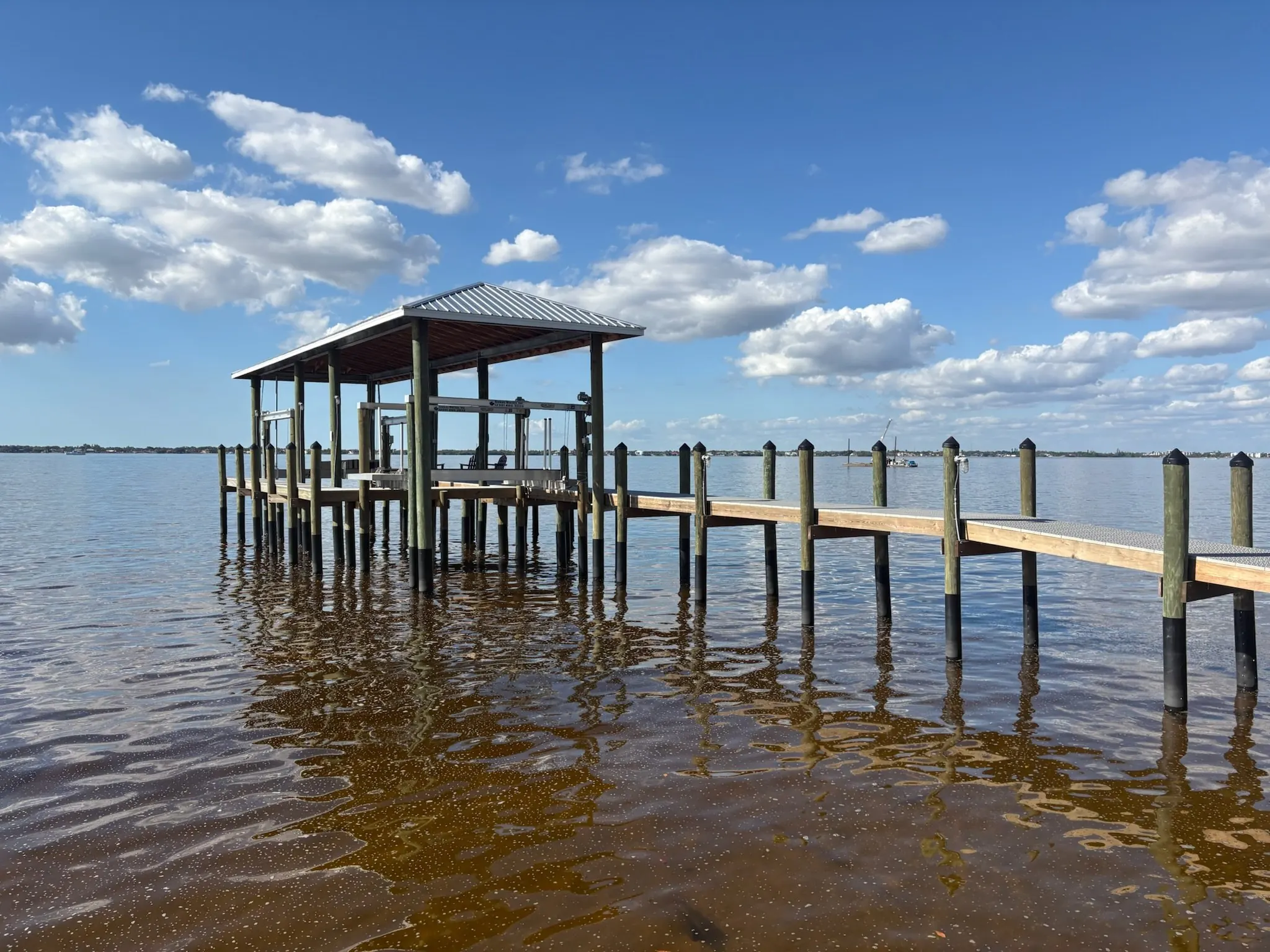Dock & Dredge: dock extending over open water to a covered boat-lift structure