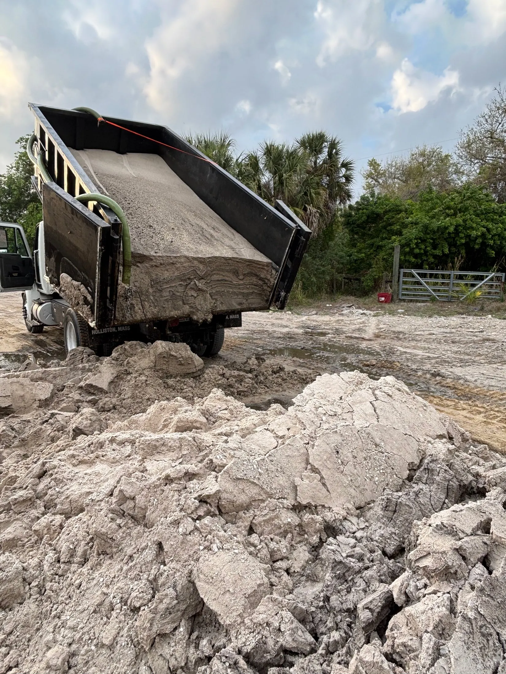 Dock & Dredge: dump truck unloading a load of pale material