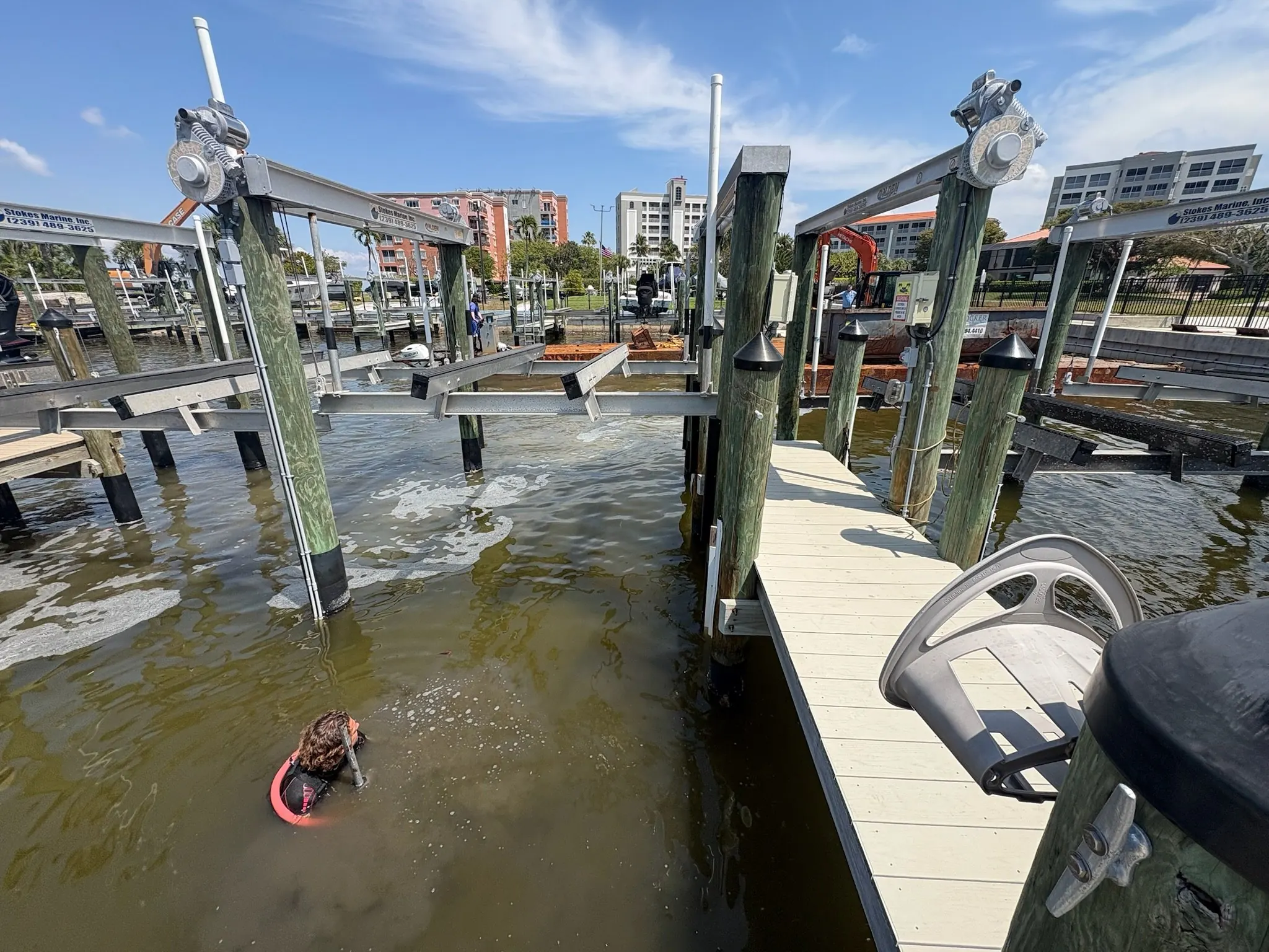 Dock & Dredge: person working in the water among docks and boat-lift structures